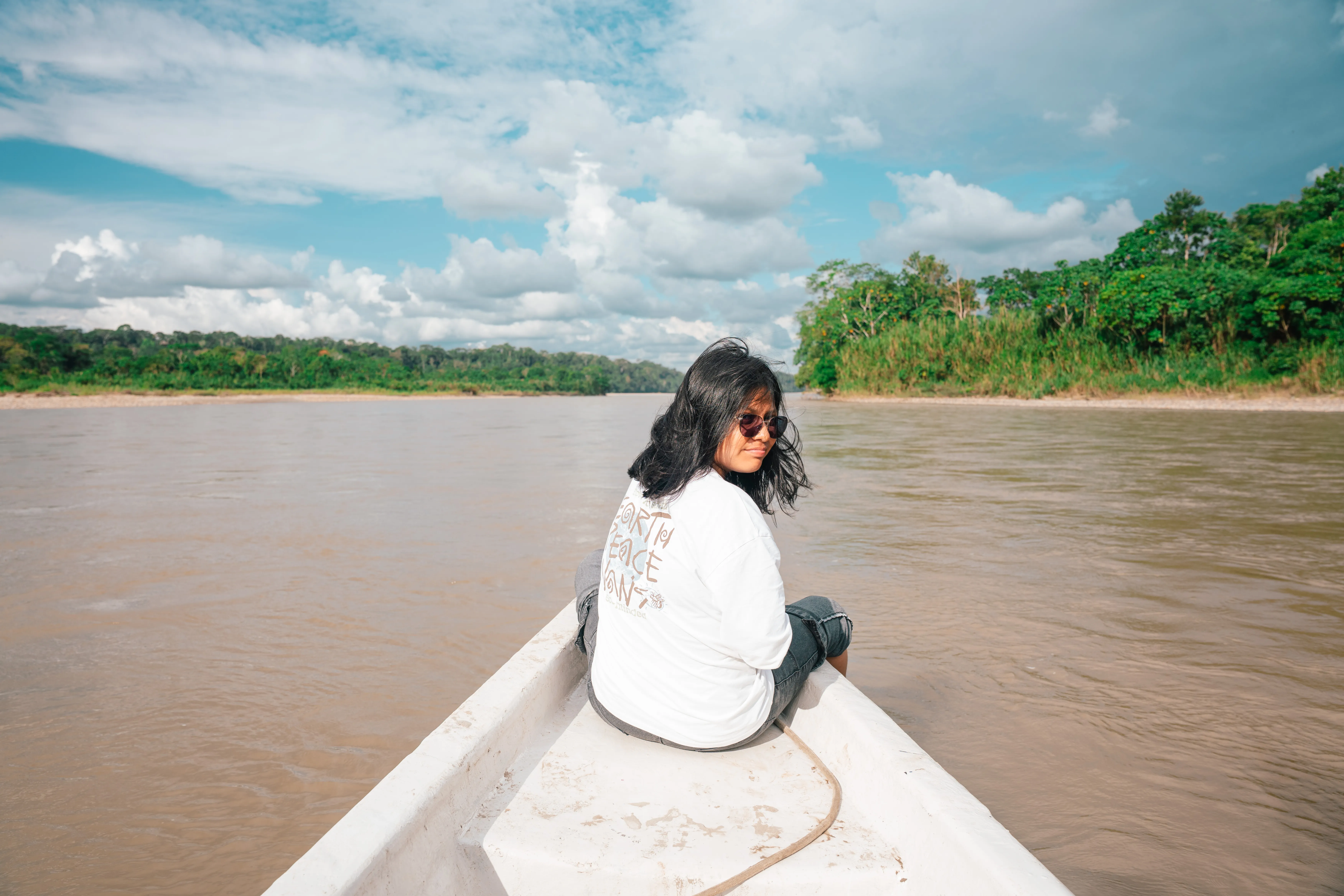 Turista en la proa de una canoa motorizada navegando el Río Napo en la Amazonía ecuatoriana
