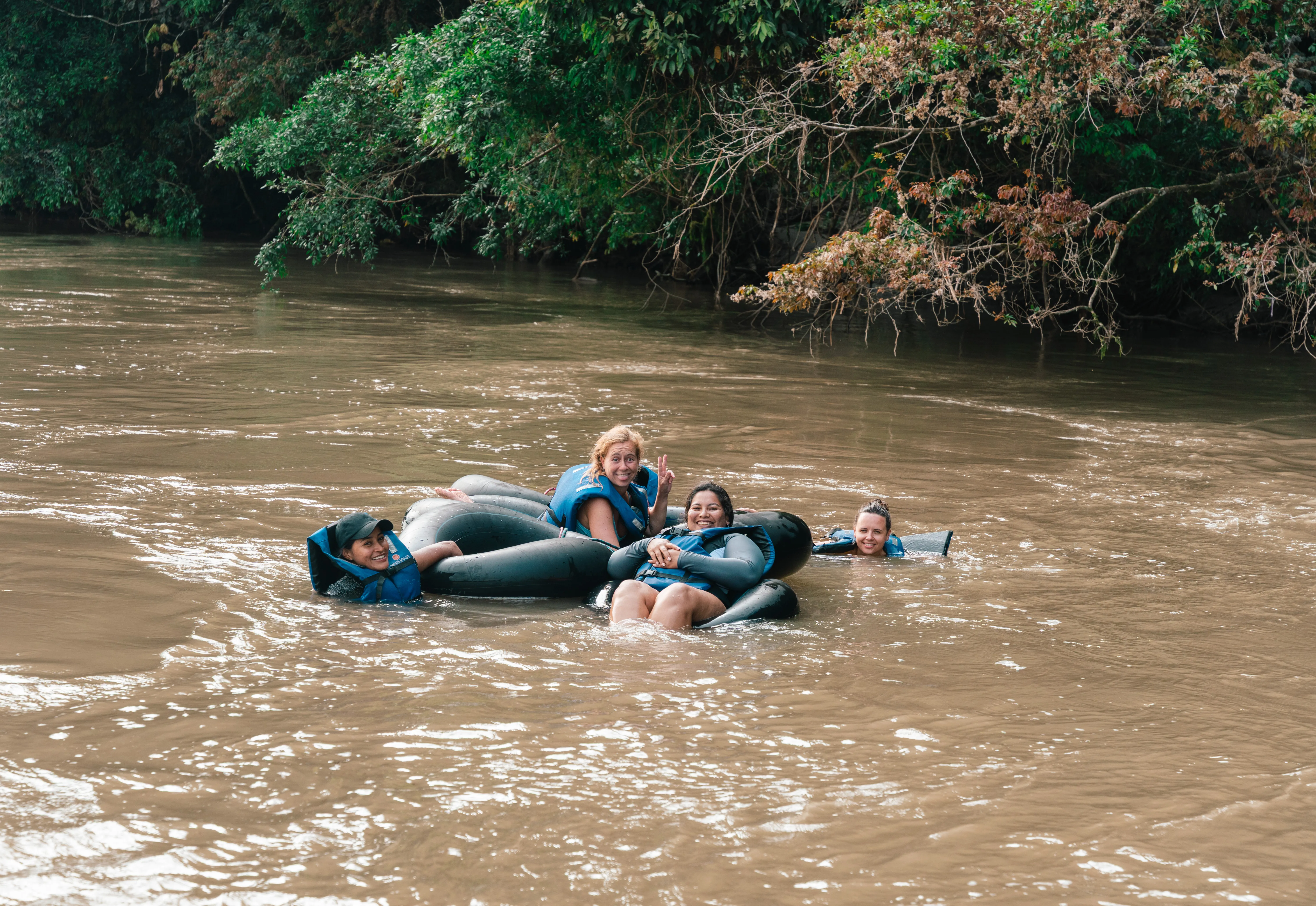 Turistas sonriendo mientras hacen tubing en boyas por el Río Napo